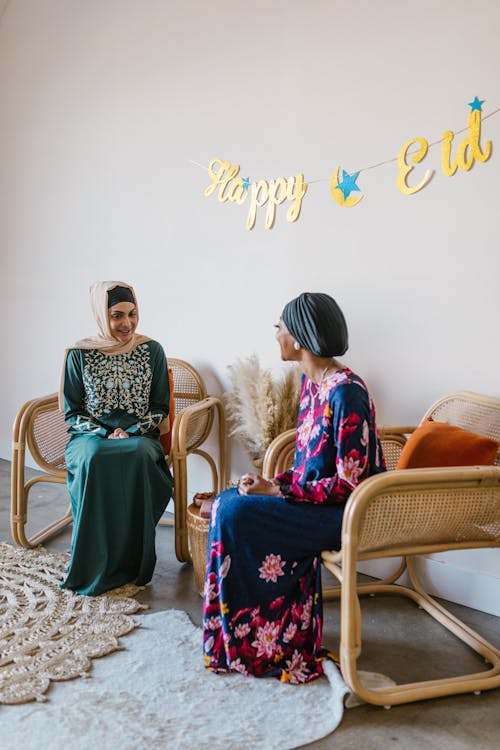 Free Women in Hijabs Sitting on Brown Wooden Armchair Stock Photo