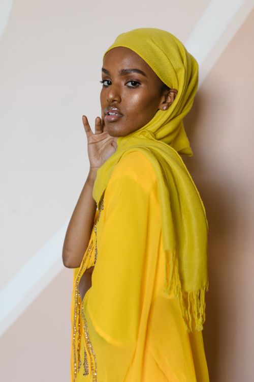Free Portrait of a young woman in yellow hijab, striking a pose in a studio setting. Stock Photo