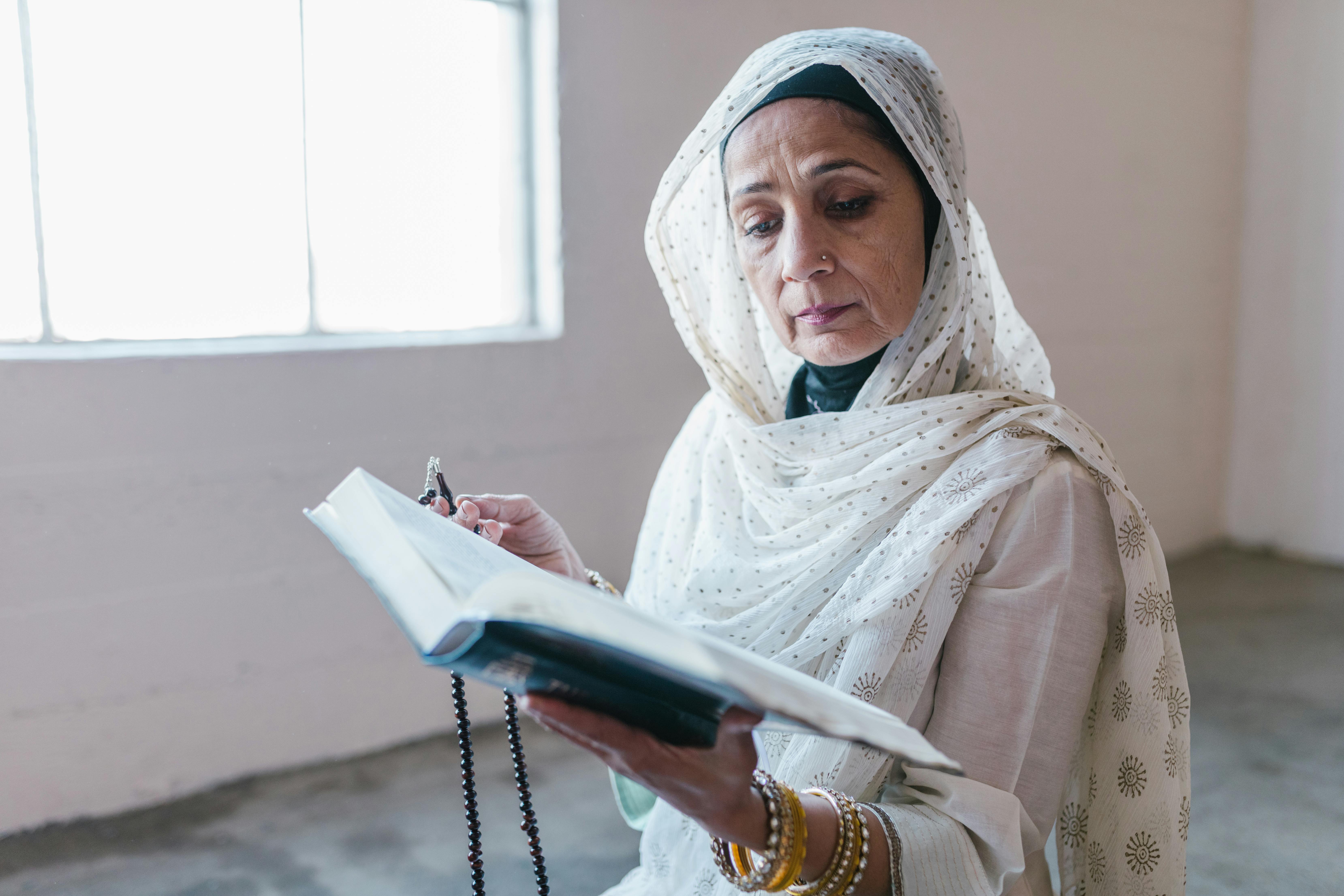 woman in white hijab holding book