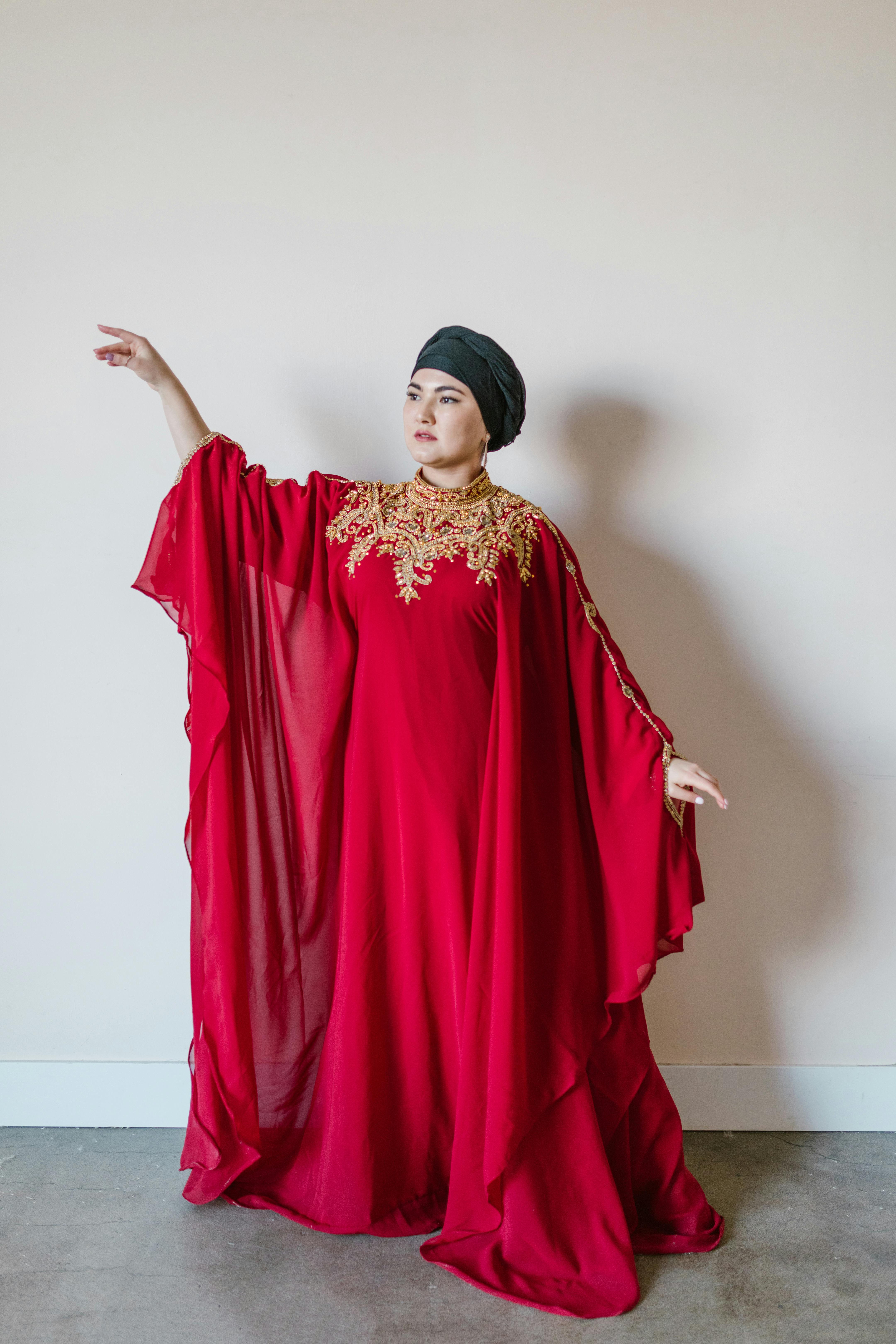 woman in red hijab standing near white wall