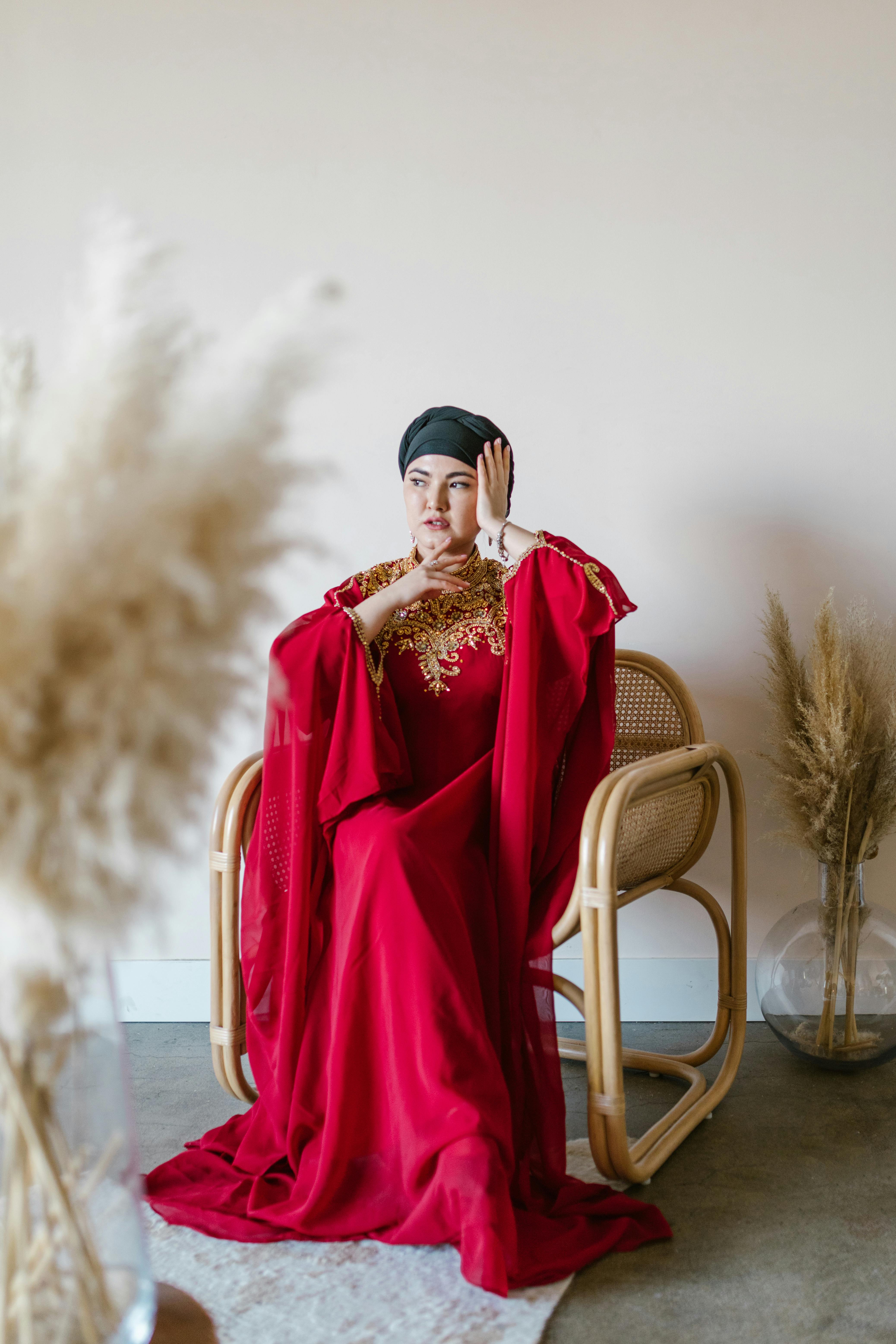 woman in red long sleeve dress sitting on brown chair