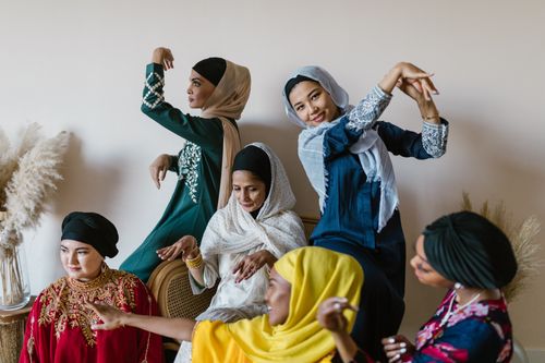 Free Group of diverse women in colorful traditional outfits joyfully celebrating indoors. Stock Photo