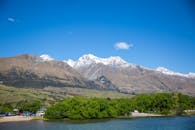 蓝天之下，白雪皑皑的山脉与郁郁葱葱的绿色植物构成了一幅迷人的景色