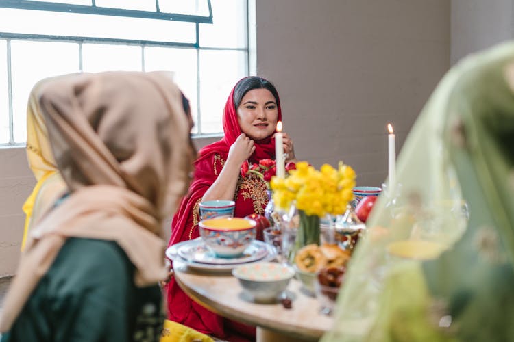 A Woman In Red Hijab Sitting At The Table