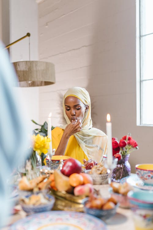 Woman in White Hijab Sitting By The Table With Food