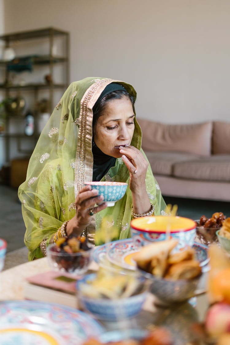 Woman In Green Hijab Eating While Holding A Bowl