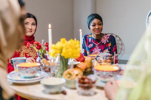 Free Women in colorful attire enjoy a festive meal with traditional food and decor. Stock Photo