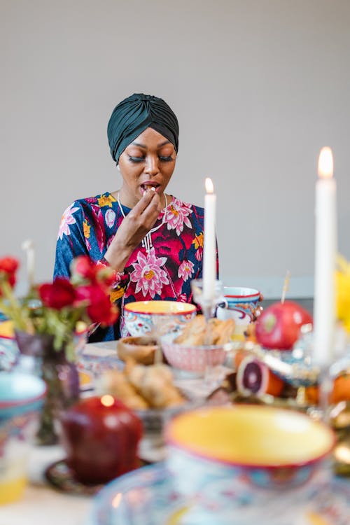 Woman Wearing a Headscarf and Floral Print Top Eating