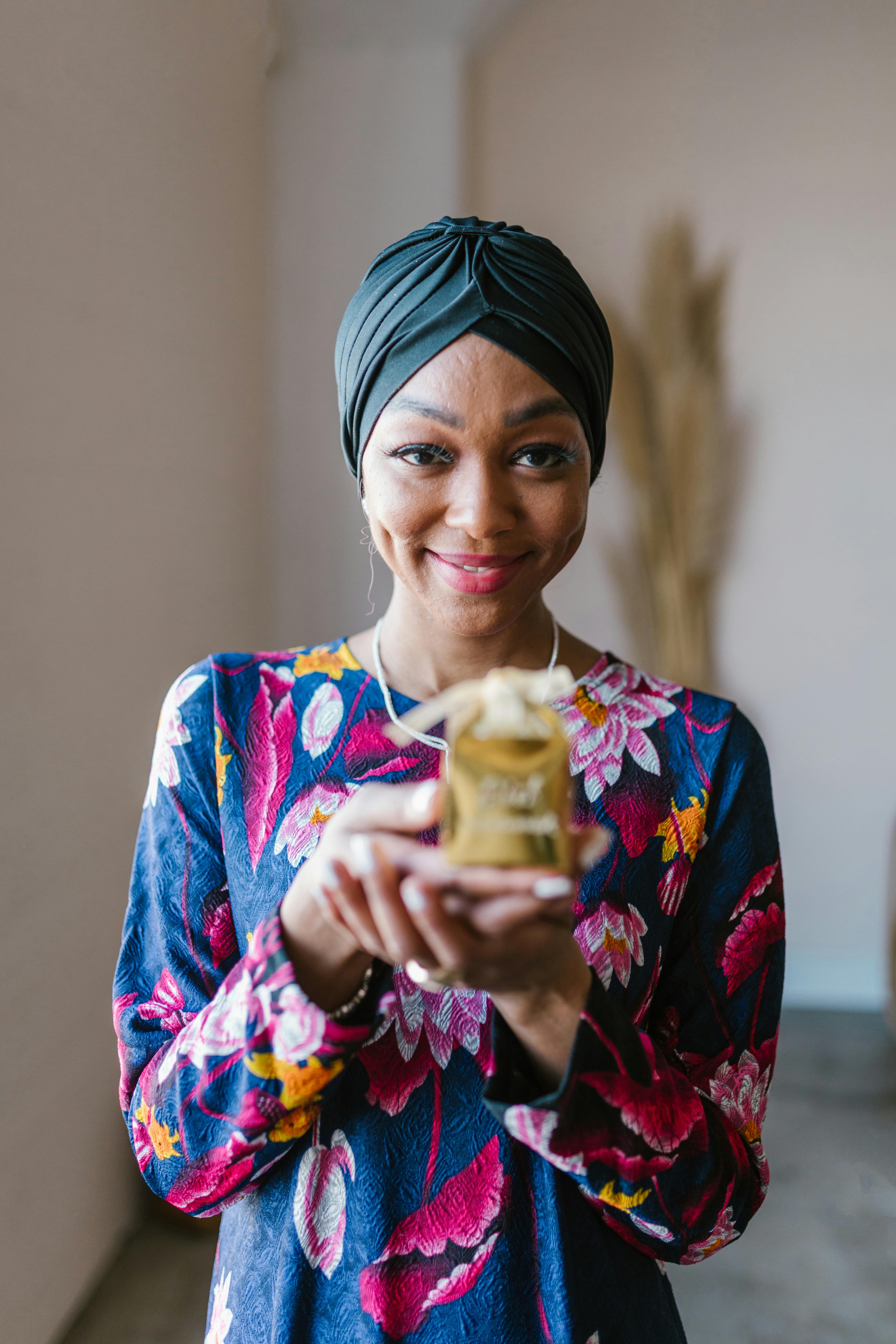 一位戴头巾、手持金色礼品盒、面带微笑、穿着花卉服装的女子肖像