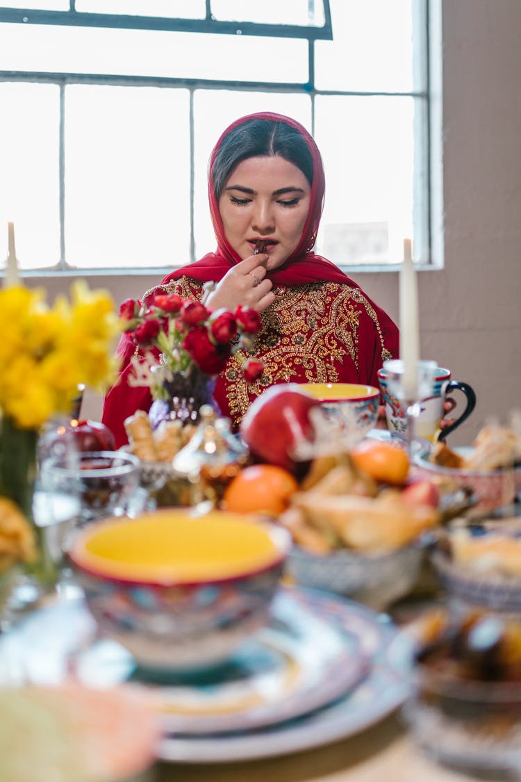 Woman In Red Hijab And Traditional Clothing Eating