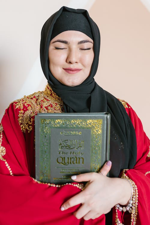 Free Woman in Black Hijab Holding A Holy Book Stock Photo