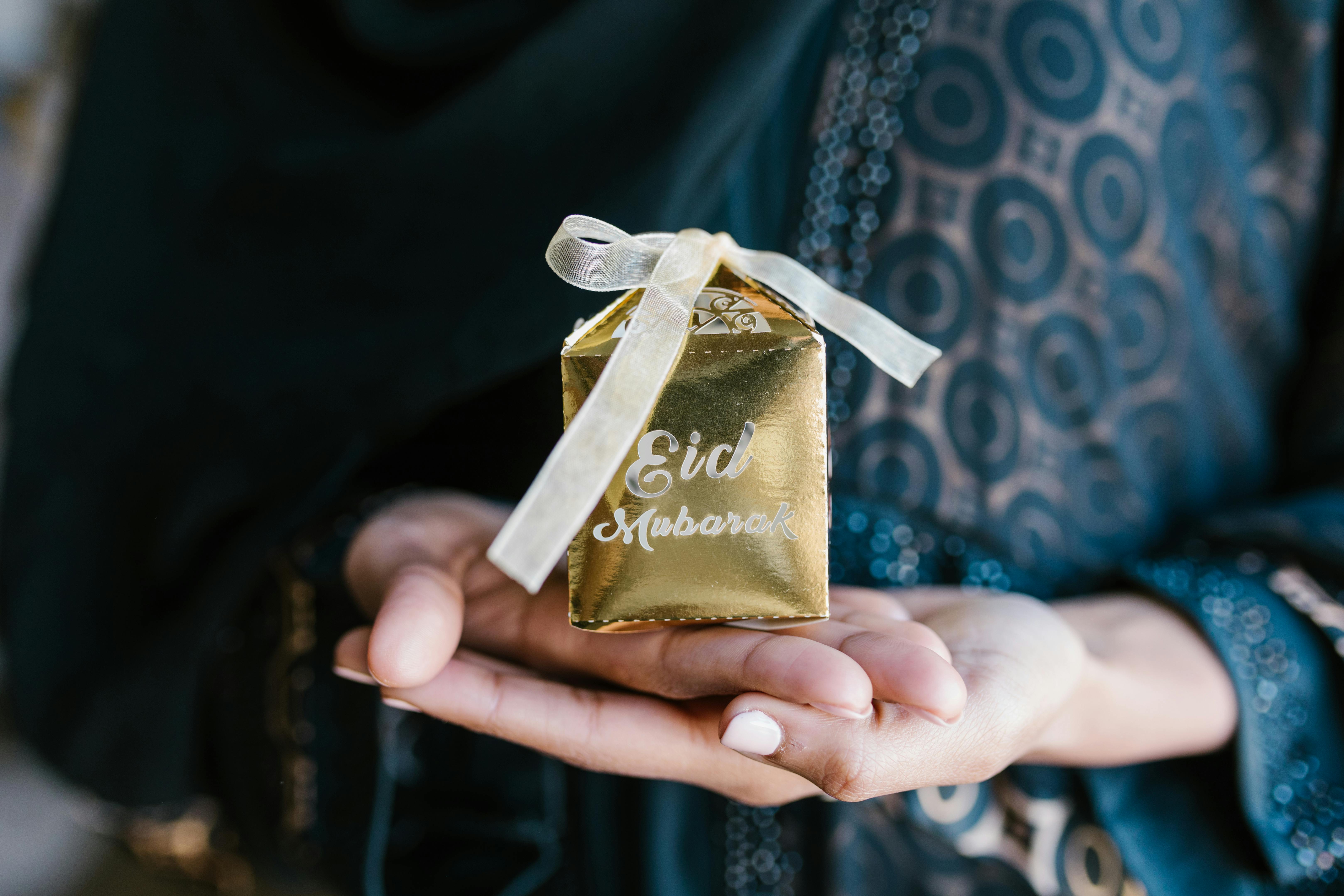 a gold gift box on a woman s hands