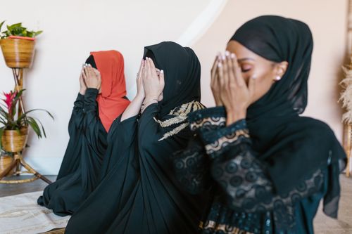 Free Three Muslim women in hijabs engaged in prayer indoors, showcasing unity and spirituality. Stock Photo