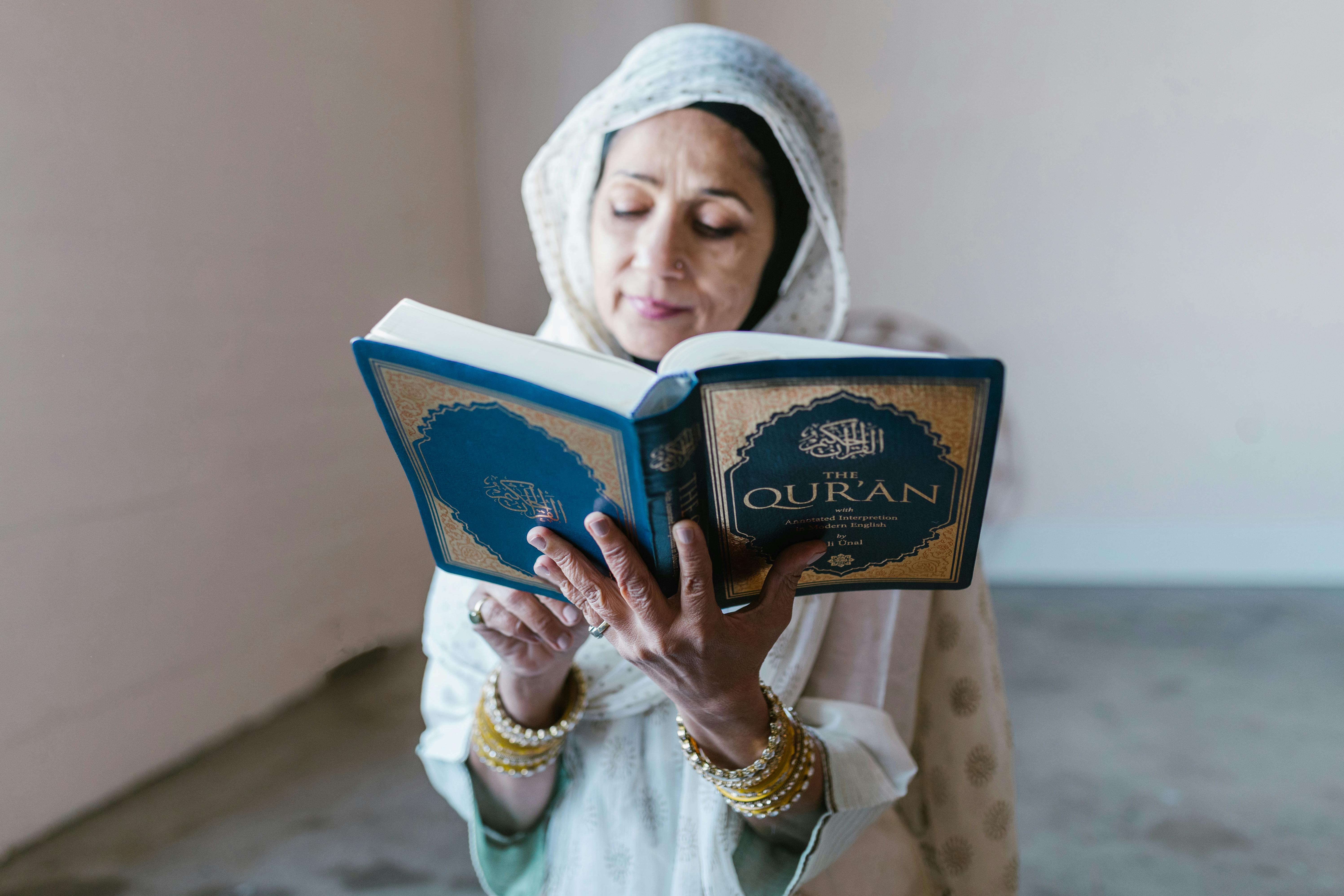 woman in white hijab holding blue book