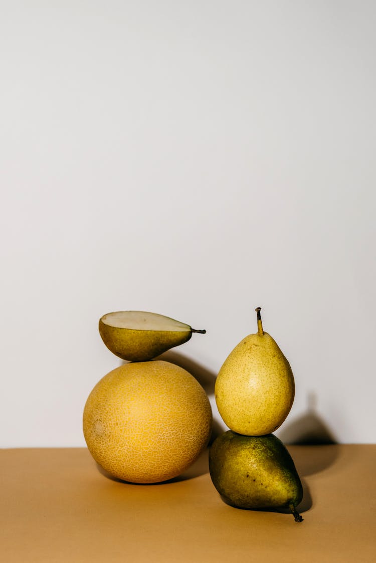 A Half Sliced Pear On A Cantaloupe Beside Pears