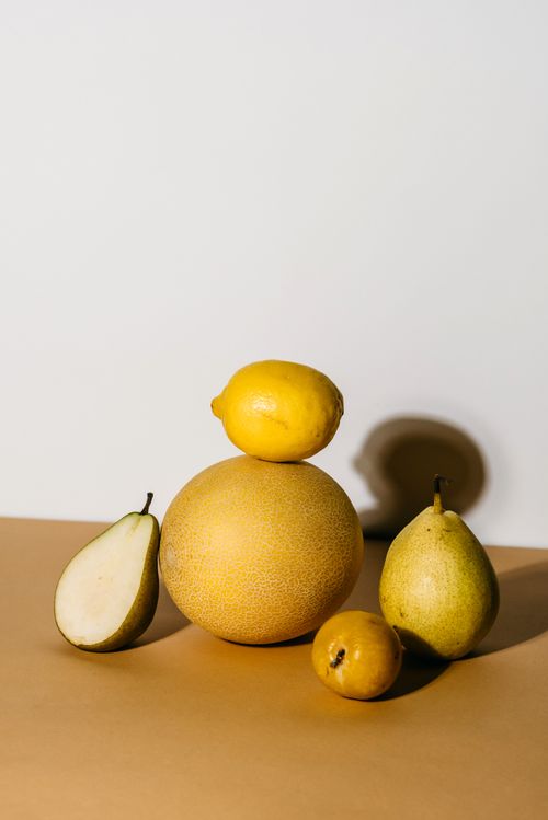 Free Arranged fruits including melon, lemon, and pears in a minimalist setting. Stock Photo