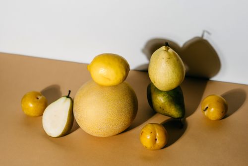 Free A beautifully arranged still life of fresh fruits including melon, lemon, and pear. Stock Photo