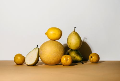 Free A collection of fresh pears, melon, and lemon creatively arranged on a minimalist background. Stock Photo