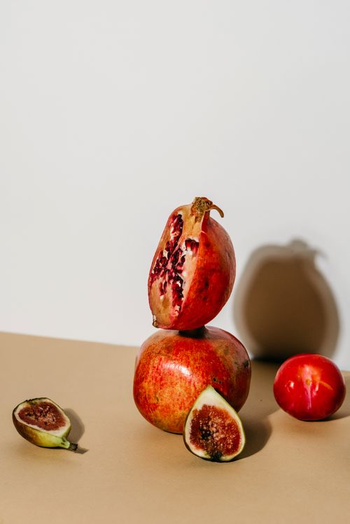 Free Artistic composition featuring fresh pomegranates and figs against a minimalist background. Stock Photo