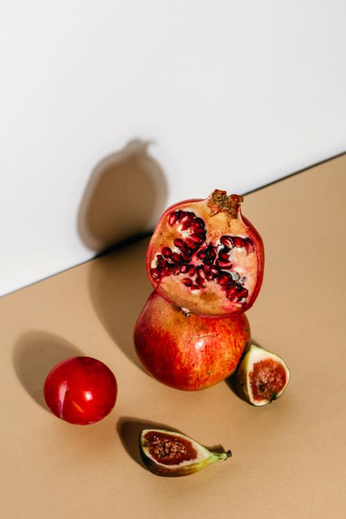 Free Artistic composition of ripe pomegranates and figs in a sunlit setting, highlighting natural textures. Stock Photo