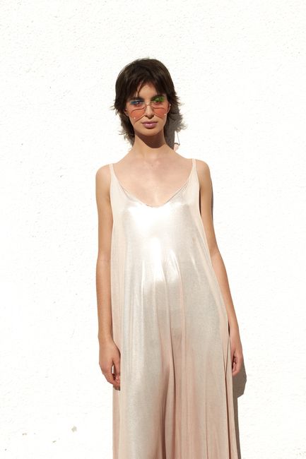 Chic woman in sunglasses and elegant dress poses confidently against a white background for a modern look.