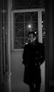 Man in Black Coat Standing beside Window