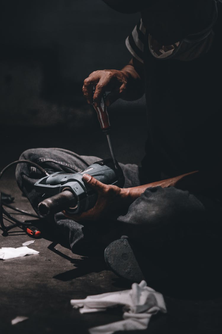 Man Sitting Cross-Legged And Fixing His Tools