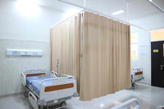Quiet hospital ward with beds and privacy curtains in Surabaya, Indonesia.