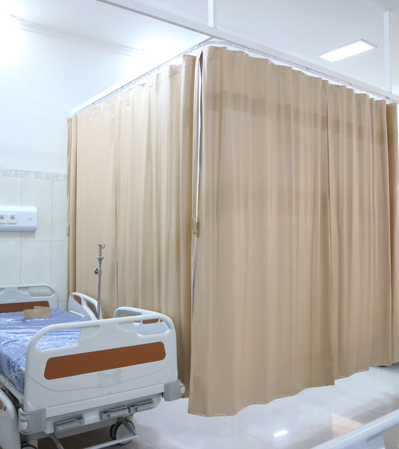 Quiet hospital ward with beds and privacy curtains in Surabaya, Indonesia.
