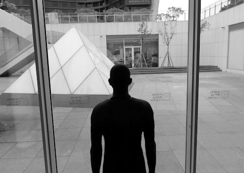 Black and white of dummy silhouette in modern building against triangle on tiled walkway in city