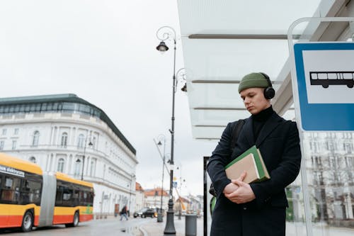 A Man with Headphones waiting at a Bus Stop