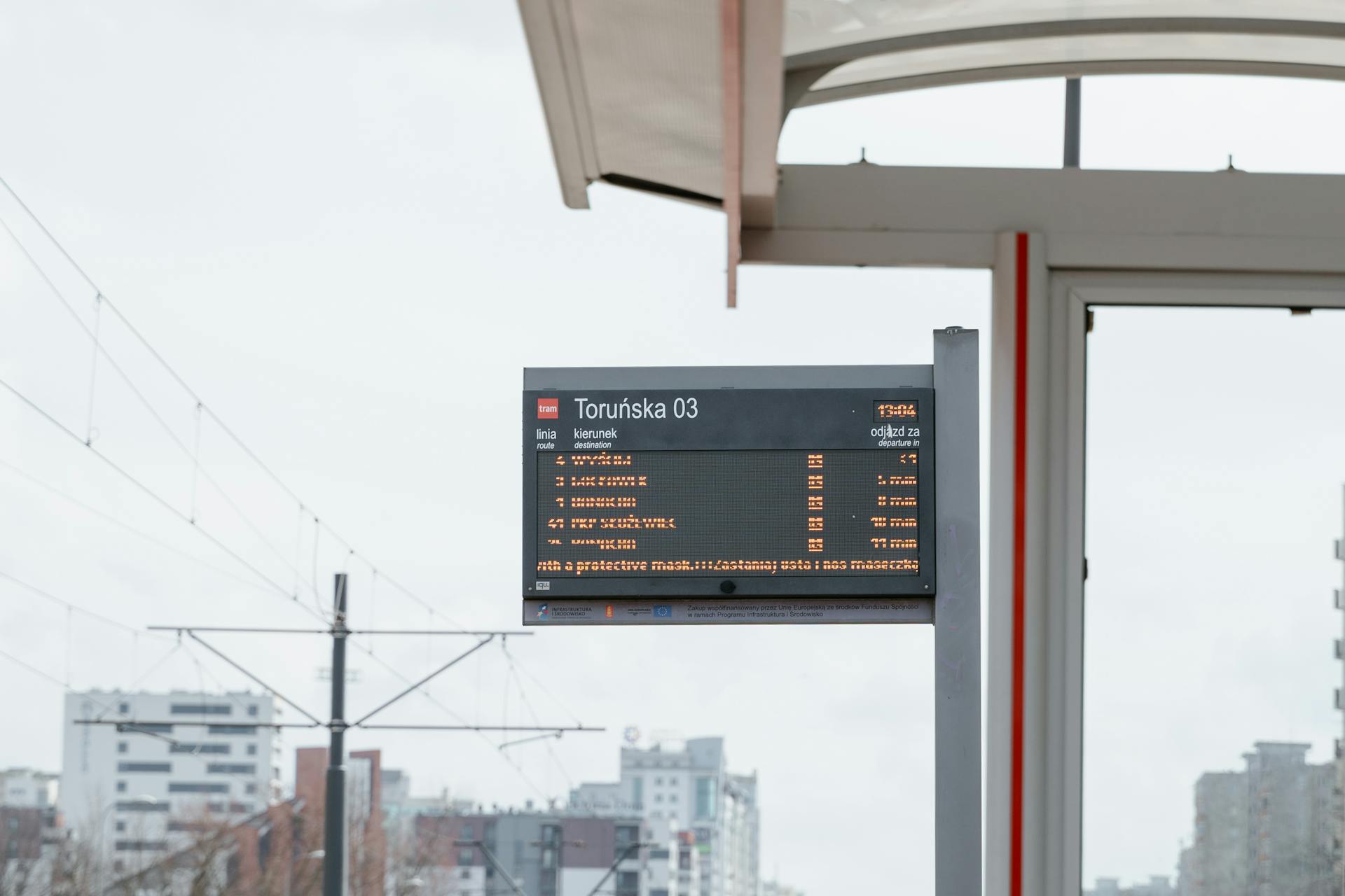 Digital tram stop sign at Toruńska 03 in an urban cityscape setting.