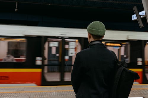 Person Wearing Green Beanie and Black Outfit Waiting for the Train