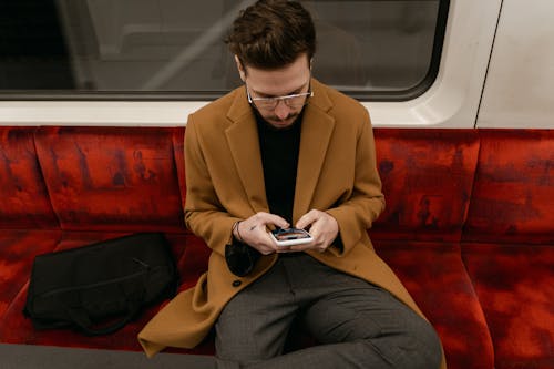 Free High-Angle Shot of a Man in a Brown Coat Using His Cell Phone Stock Photo