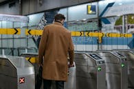 A Person in Brown Coat Entering a Subway Automated Ticket Barrier