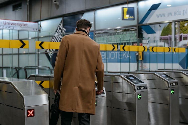 A Person In Brown Coat Entering A Subway Automated Ticket Barrier