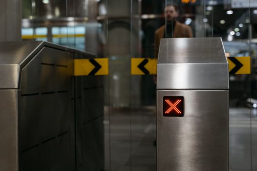 Photo by MART PRODUCTION Close-up of a stainless steel ticket barrier with red X signal indicating no entry.