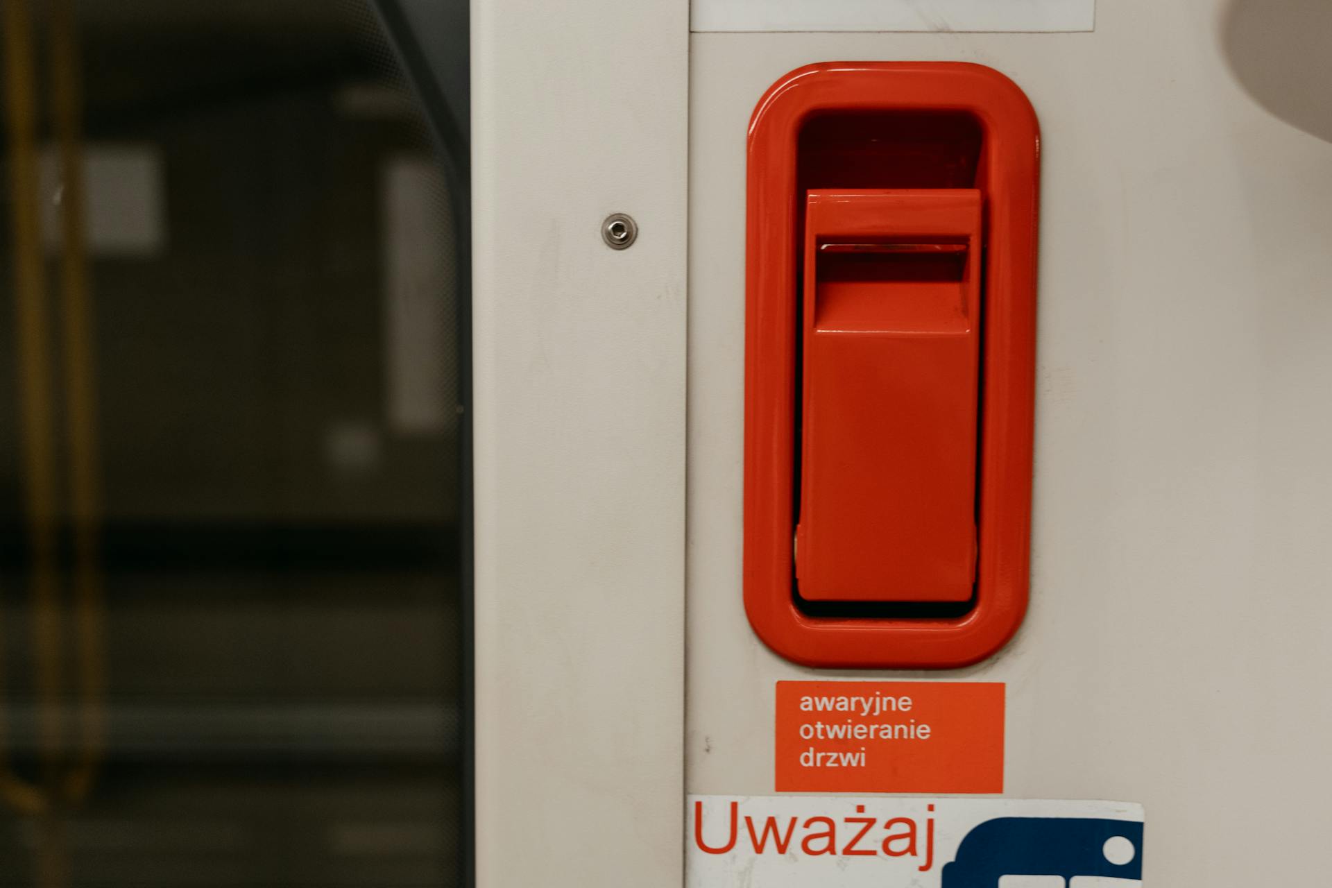 A White Door with Red Lever Above a Warning Sign