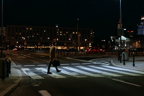 Free A Person Carrying Briefcase Crossing a Pedestrian Lane at Night Stock Photo
