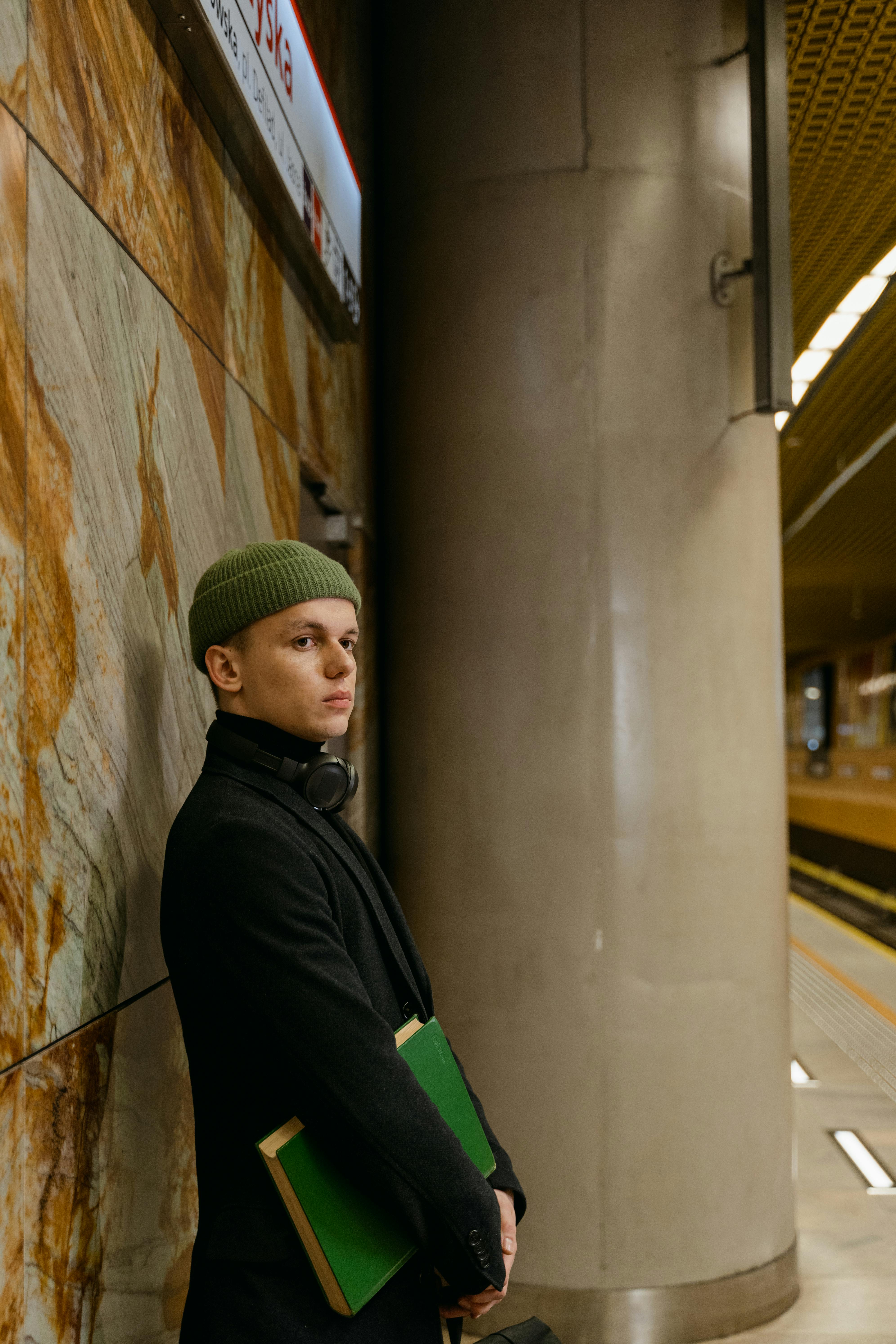 a man wearing a bonnet and a coat waiting on a train station