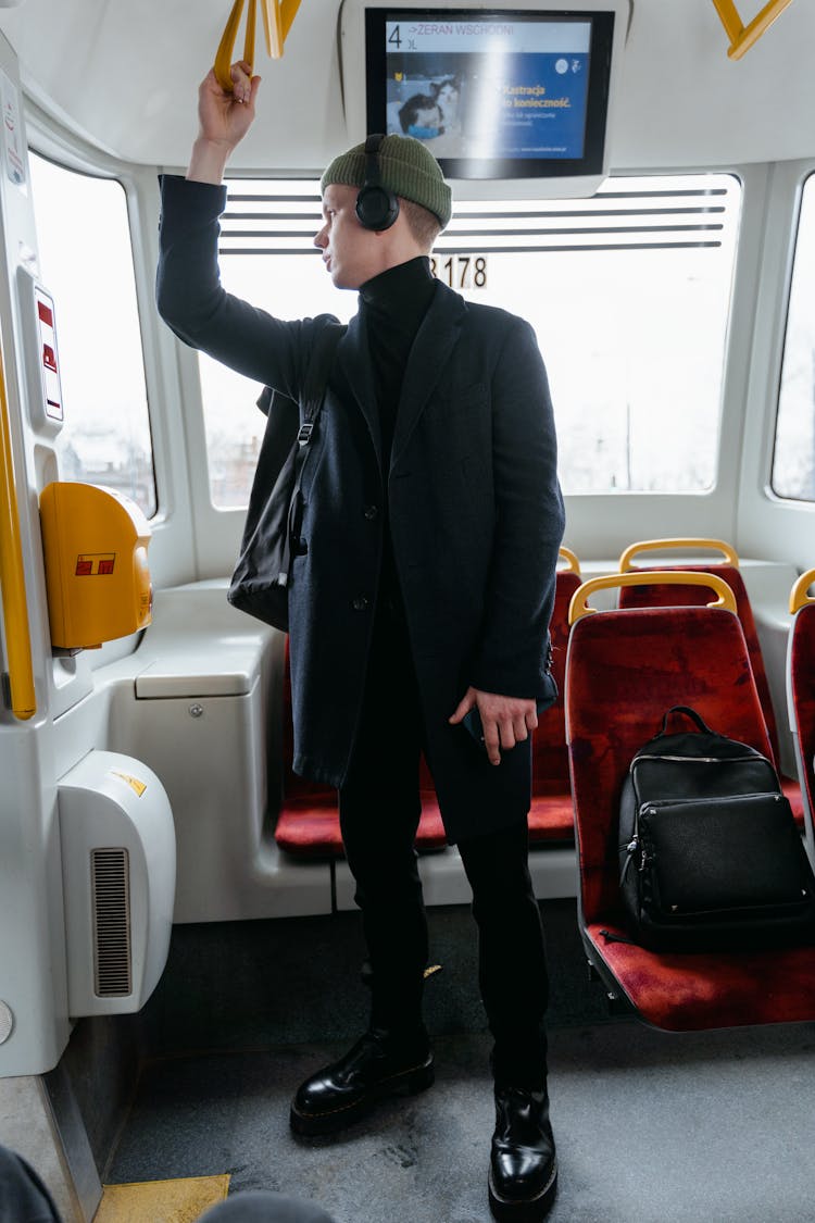 A Man In Black Coat Standing Inside The Train While Looking Over Shoulder