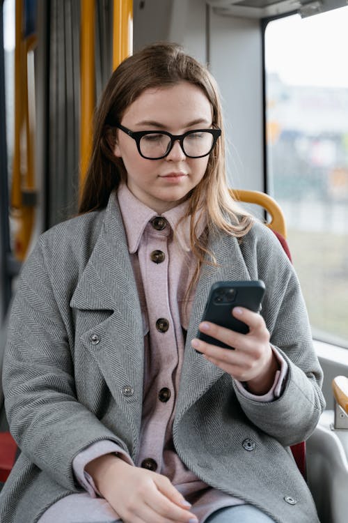 A Woman in Gray Coat Using Her Mobile Phone