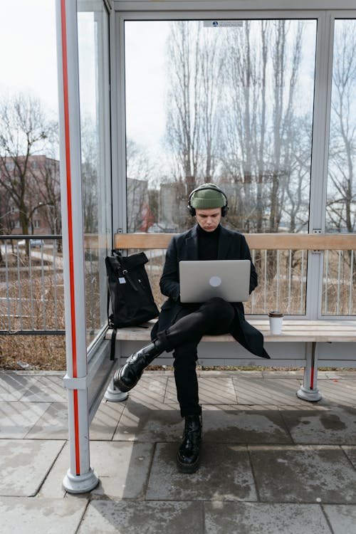 Free 
A Man Using a Laptop while Waiting on a Bus Stop Stock Photo