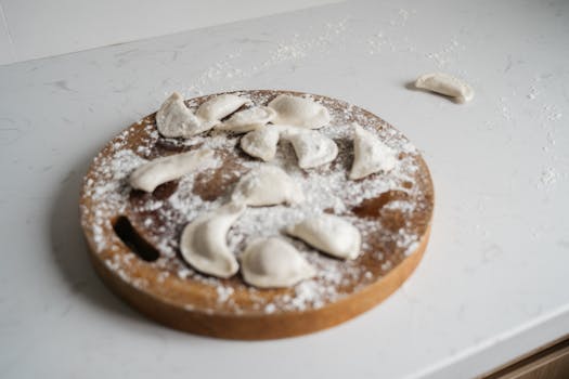 Homemade dumplings on a wooden cutting board, ready to cook. Perfect for Asian cuisine themes.