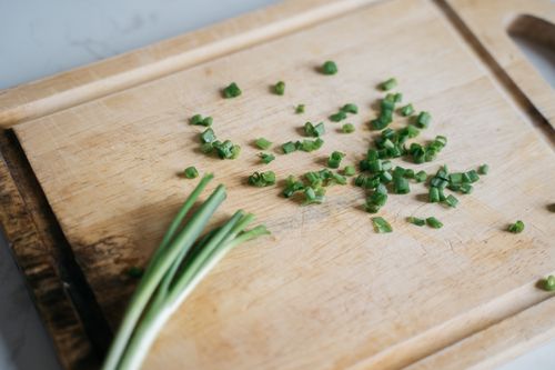 Free Freshly chopped chives scattered on a wooden board, highlighting culinary preparation. Stock Photo