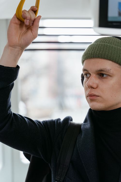 Free Portrait of a young man wearing a beanie, commuting on public transport with a blurred background. Stock Photo