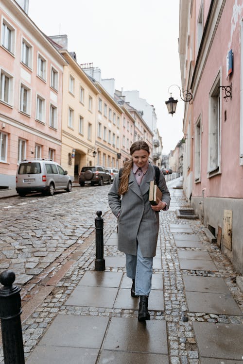 A Woman in Gray Coat Walking on the Sidewalk