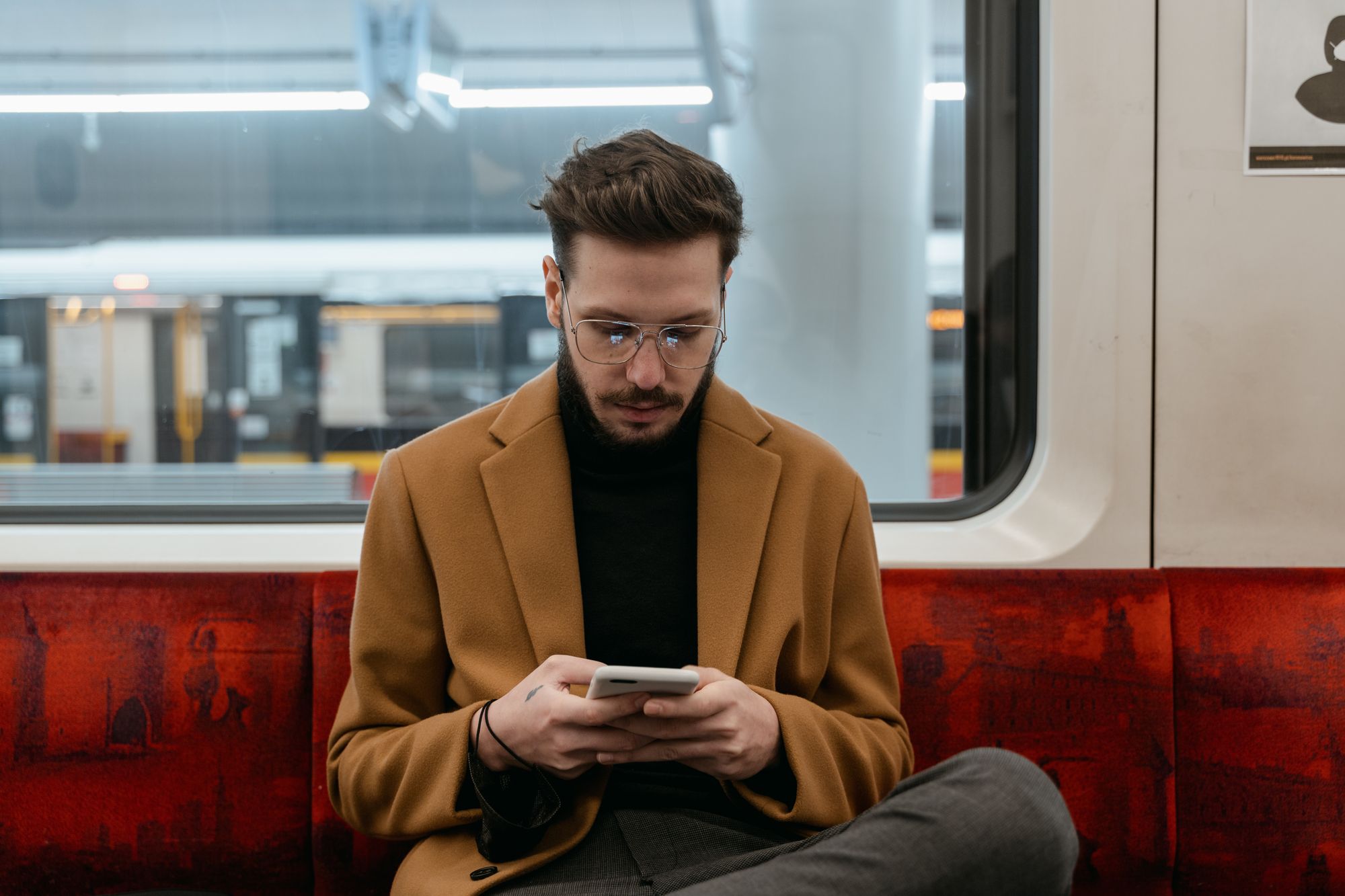 Young man calmly reading a text message on his phone while commuting
