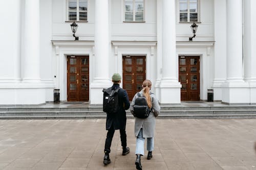 A Man and Woman Walking in front of a Concrete Building