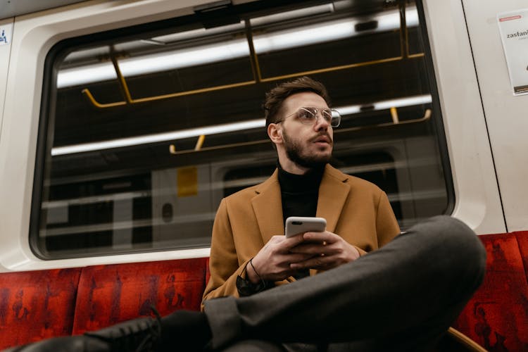 A Man Holding A Smartphone In A Train